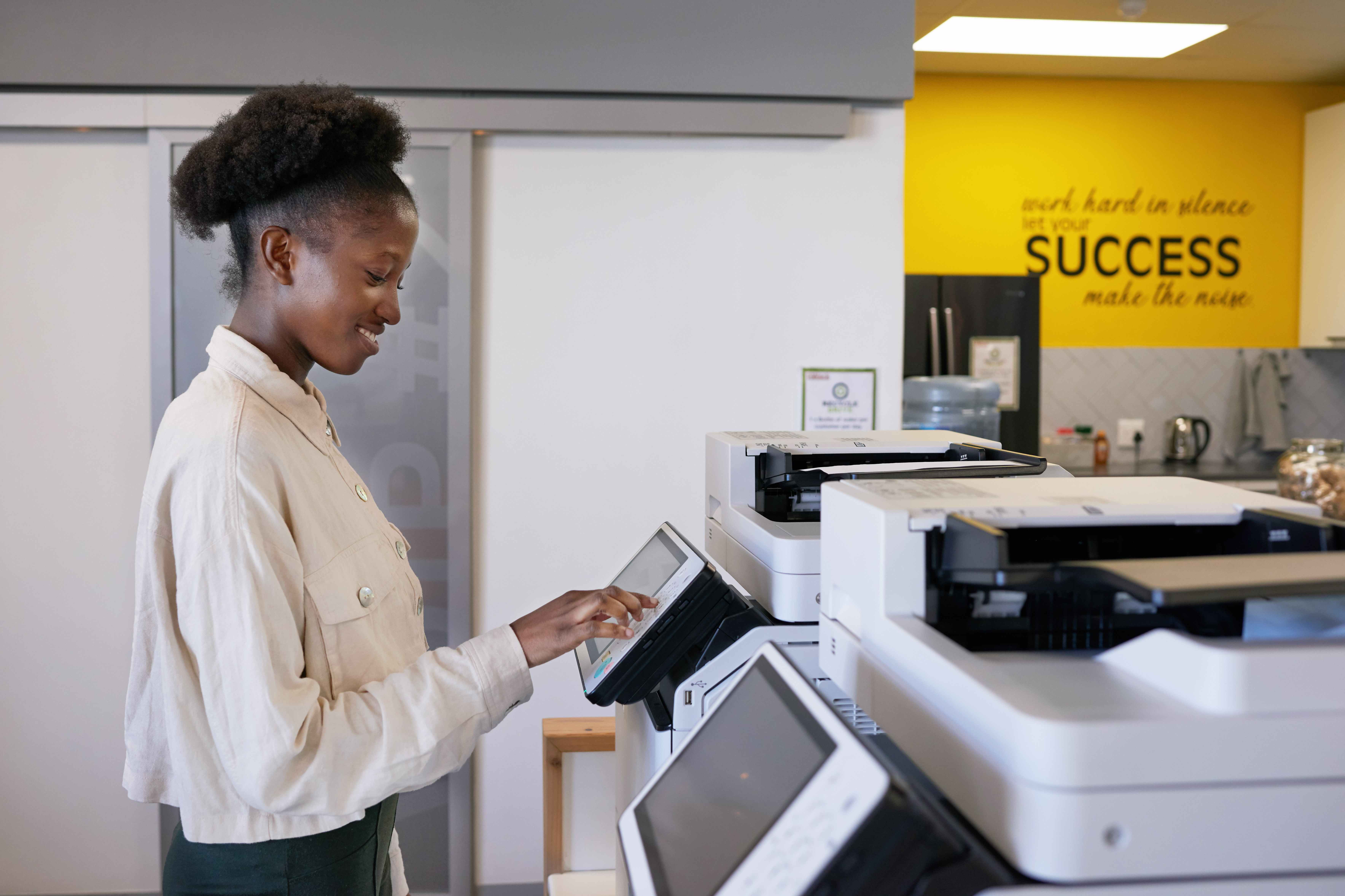 Professional business woman using modern multifunction printer in contemporary Saskatchewan office environment showcasing Vonex Business Solutions expertise and customer success